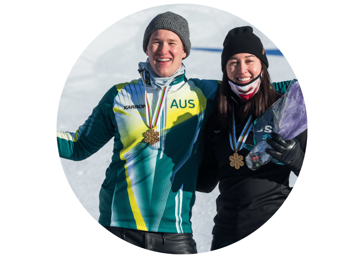 Two people standing in the snow with medals around their necks.